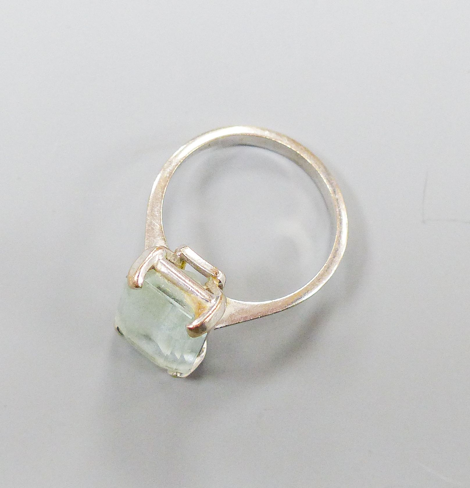 A 750 white metal and emerald cut aquamarine set ring, size O, gross weight 4.6 grams.